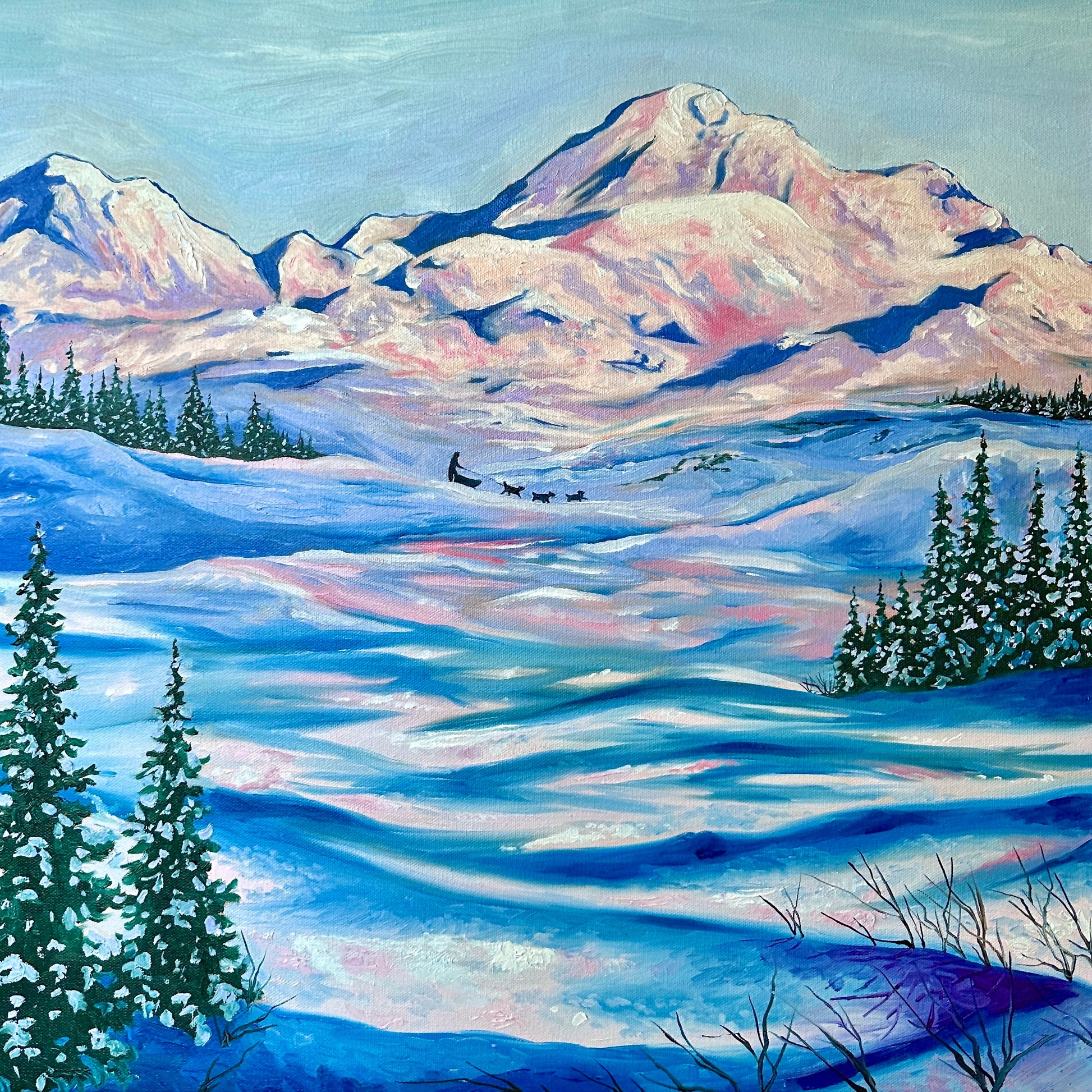 A painted landscape of Alaskan mountains with vast fields of snow in the foreground, and a small dogsled team in the distance. By artist AnnMarie Henderson.